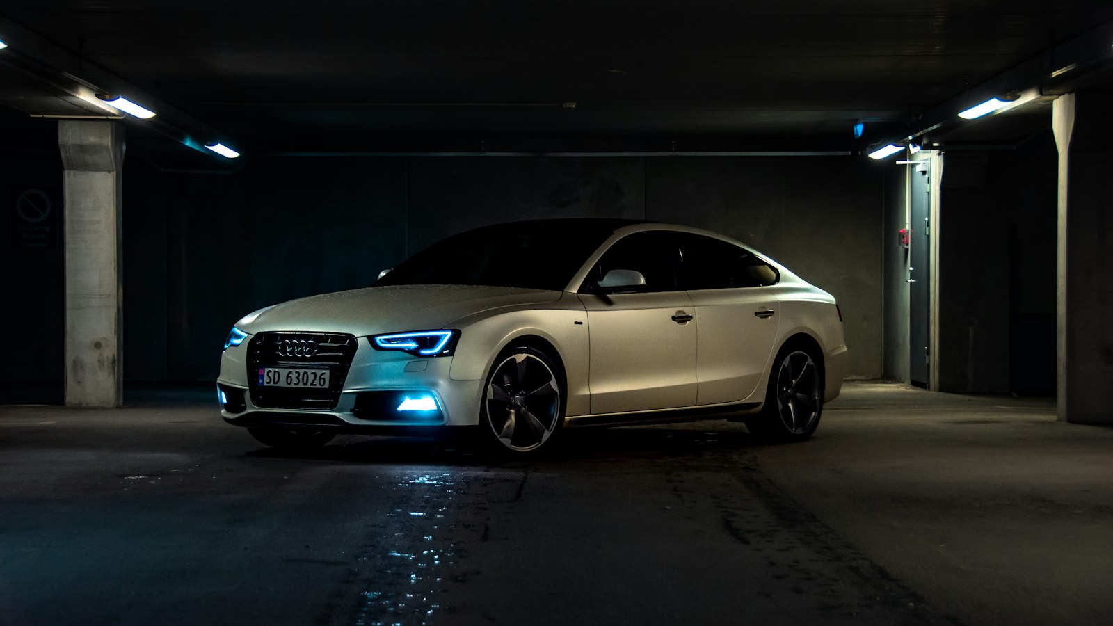 Silver Audi parked in a dark garage under strip lights