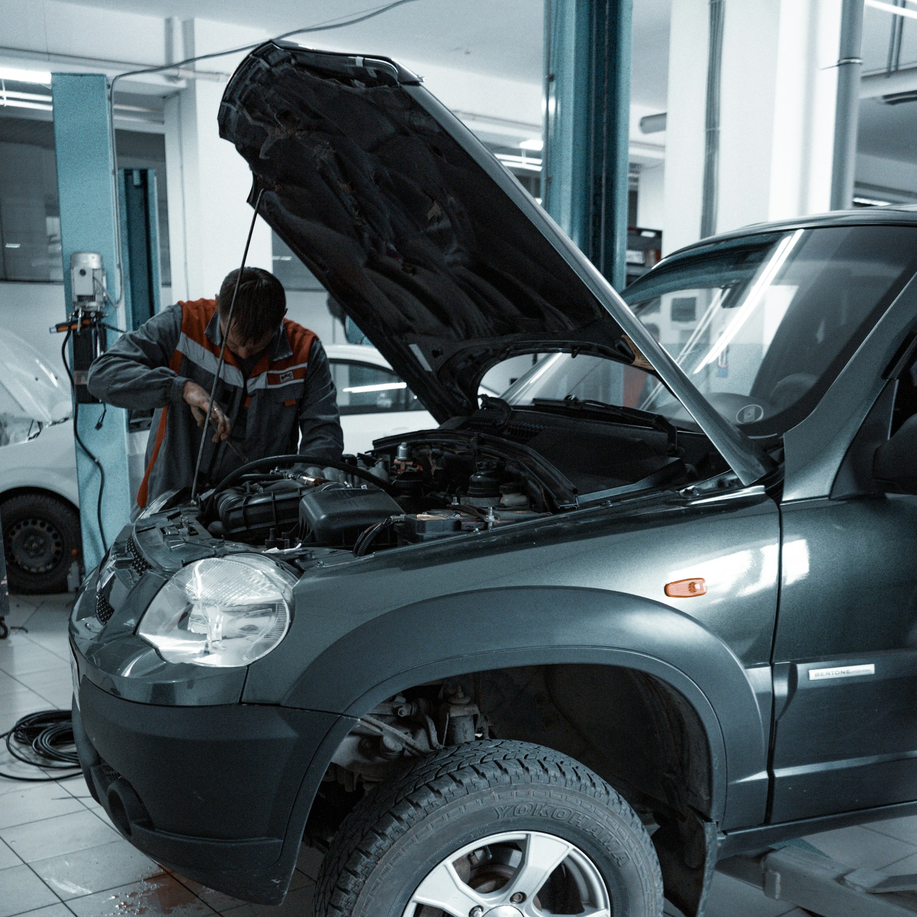 Car on a workshop lift with its hood open and front wheel arch visible
