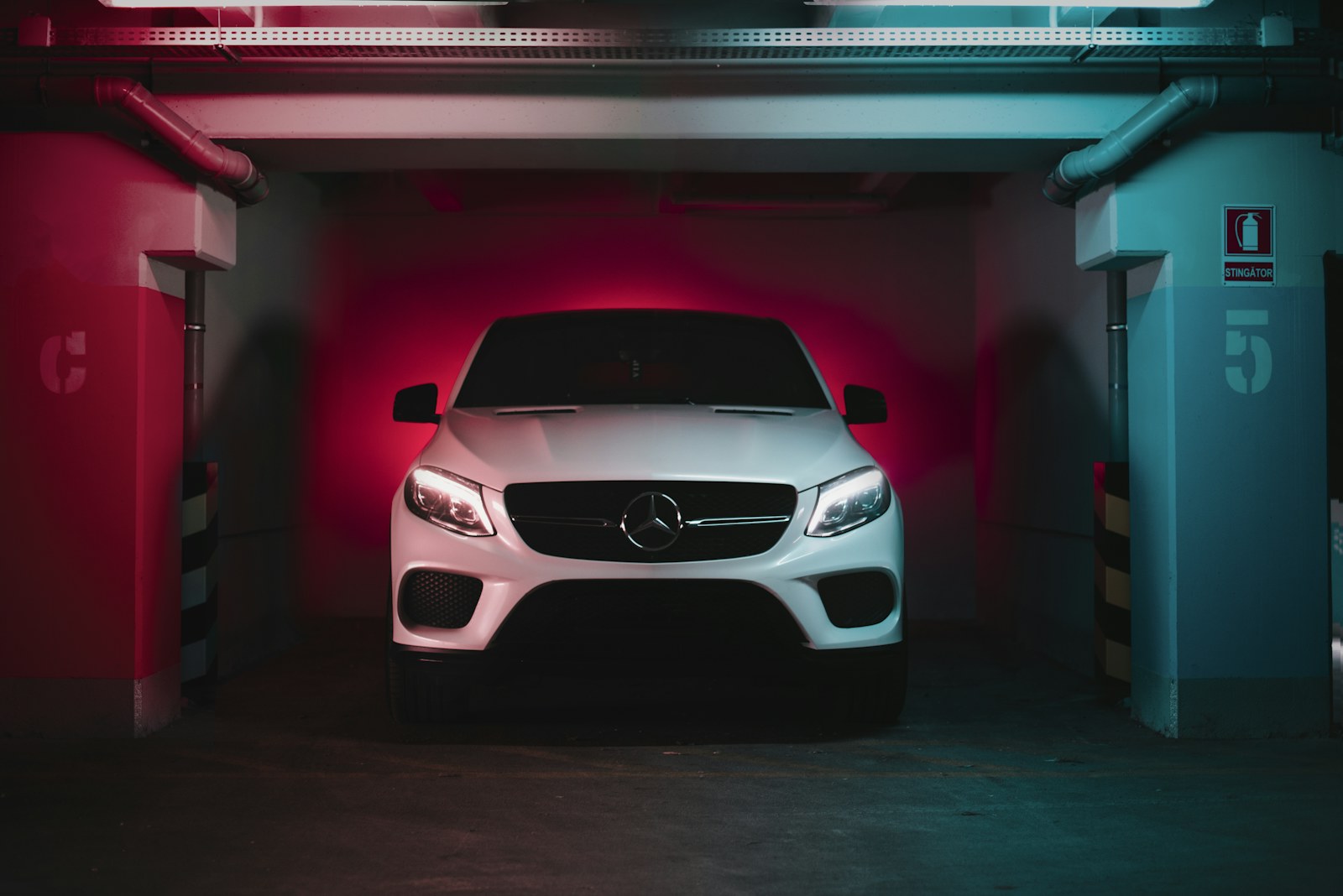 White Mercedes in a garage bay lit with red light