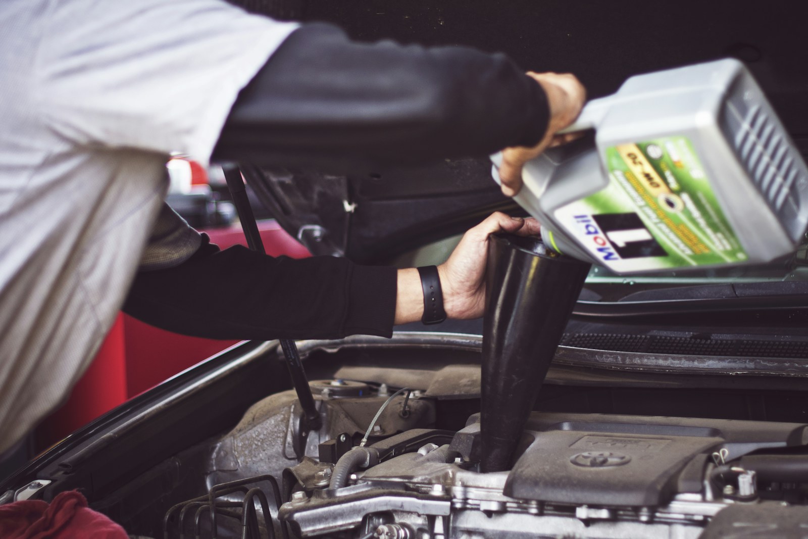 Mechanic pouring fresh engine oil into an engine