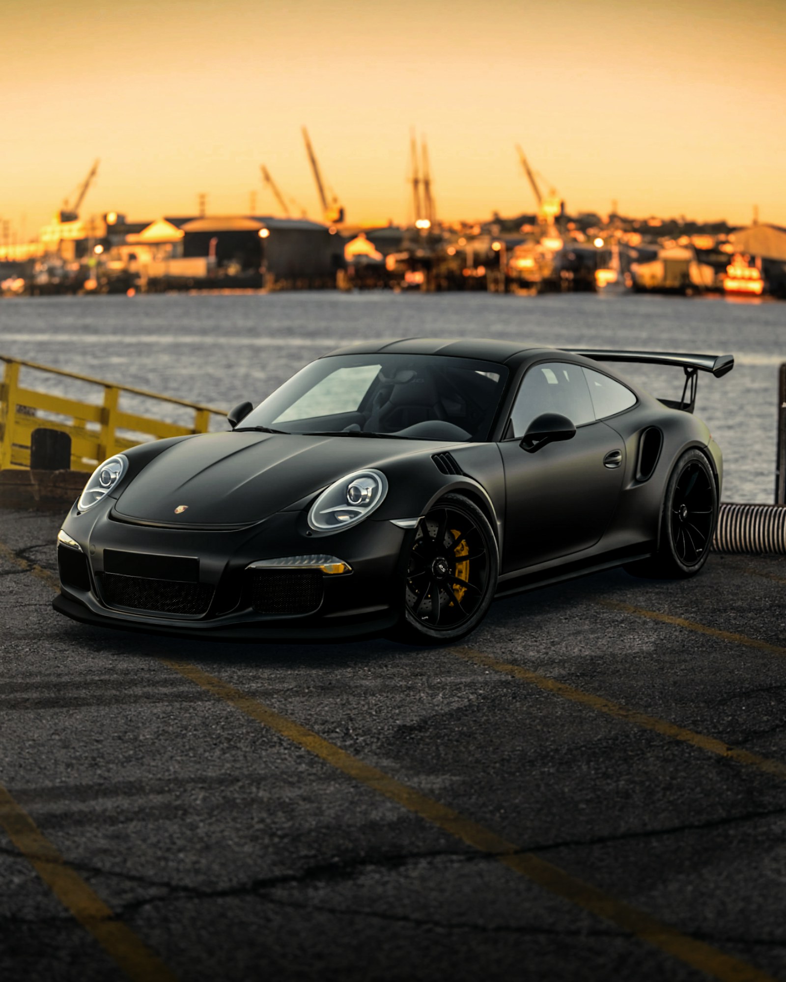 Black Porsche 911 on a quayside at dusk
