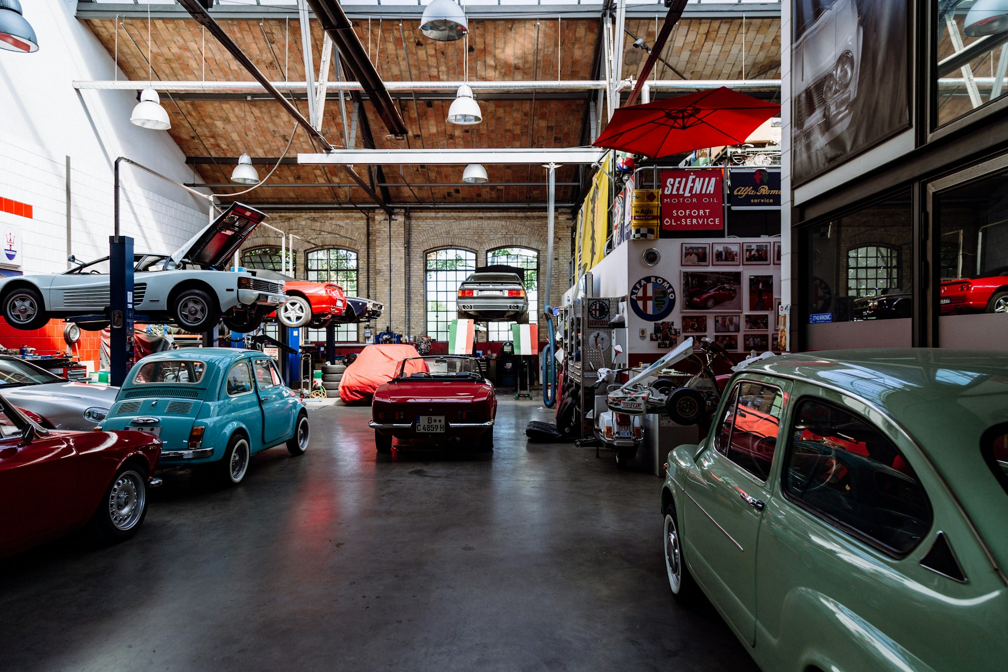 Wide view of a busy workshop floor with classic cars on lifts